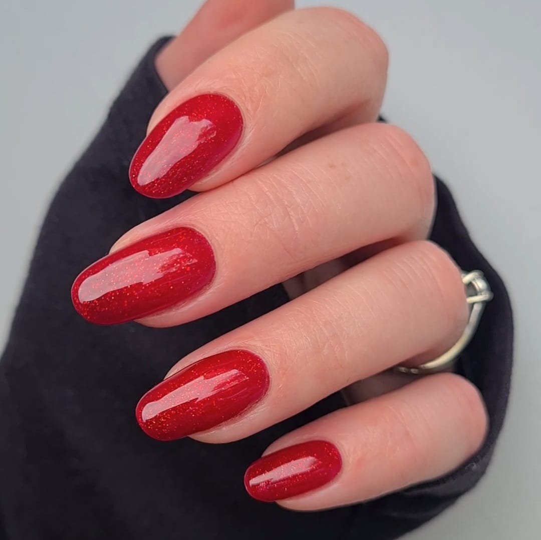 Moulin Rouge Nail Polish – Farbwirkung auf lackierten Nägeln; Farbton ein tiefes Kirschrot mit feinem Goldglitter